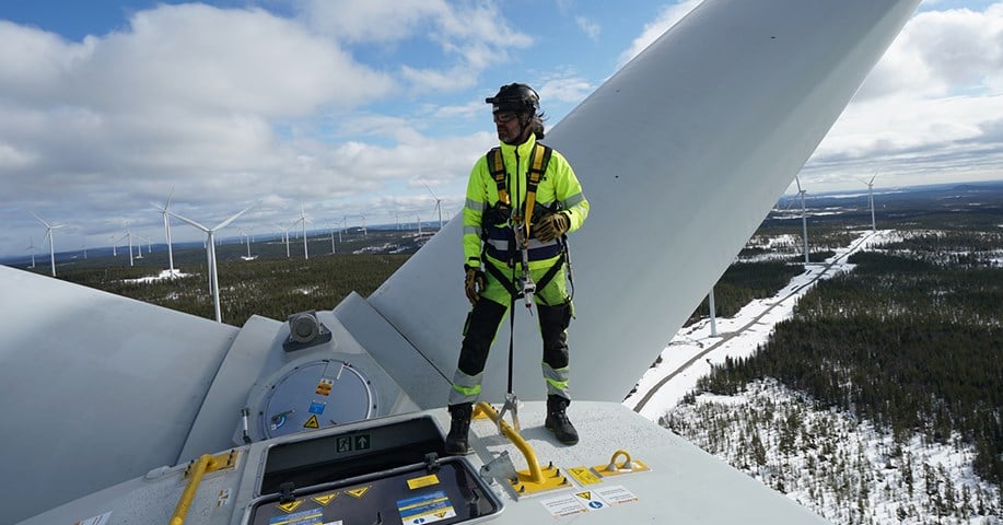 Besiktningsingenjör står längst upp på ett vindkraftverk. 