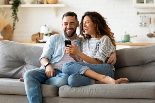 Man and woman sitting together on the couch looking at a phone