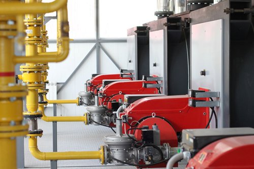 Industrial gas burners with yellow piping in a mechanical room, showcasing modern heating equipment installation