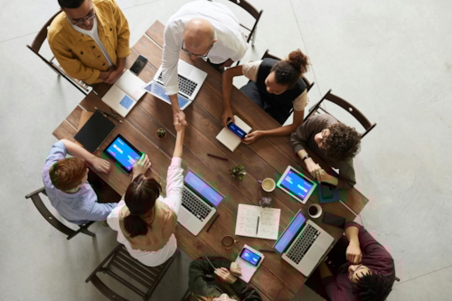 People sitting in an office working on their laptops, shaking hands