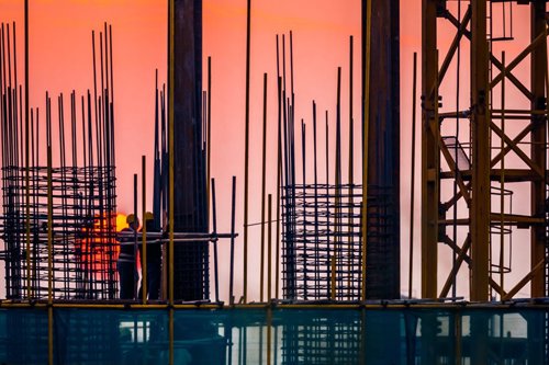 Steel building site with builders and sunset