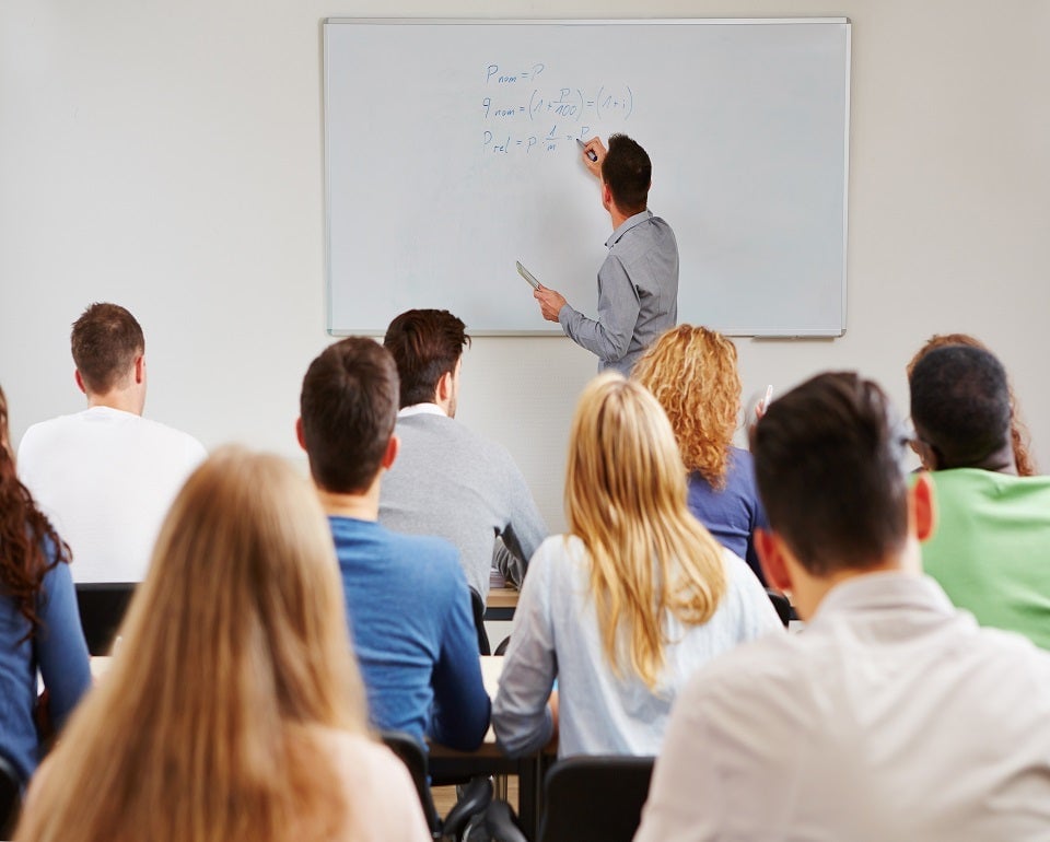 College classroom with students listening to a male Kiwa trainer writing equations on a whiteboard