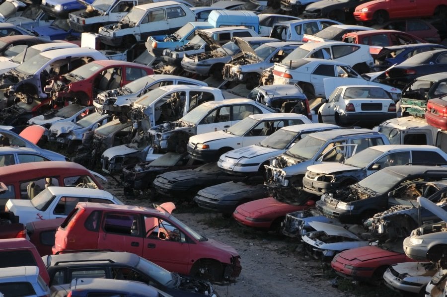 Een terrein met meerdere beschadigde en gesloopte auto's, gestapeld