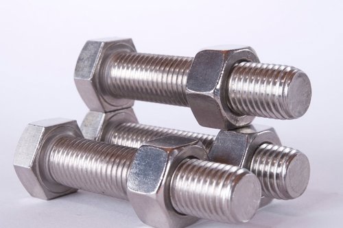 Set van drie metalen bouten en moeren op een witte achtergrond.