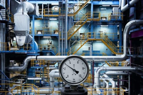Industriell anläggning med stora rör, metalltrappor och en tryckmätare i förgrunden i en bild som förmedlar att Kiwa arranger branschseminariet Kraftvärmedagarna hösten 2026.