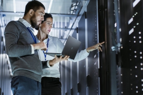 Kiwa experts, a woman and a man, looking at computer servers