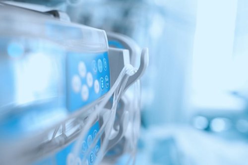 Close-up of hospital infusion pump with control panel and cables, highlighting medical technology in a healthcare setting