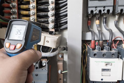 En elektriker använder en termopistol för att analysera underledningar och komponenter för att ta reda på överströmsbelastningar och avvikelser för en elanläggning.