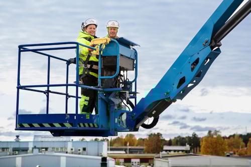 En man och en kvinna står i en lyftkorg i bomlift, högt upp i luften.