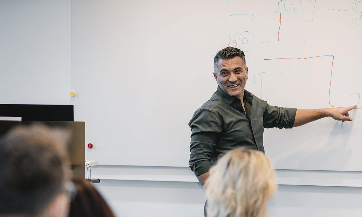 Kiwa trainer in a classroom giving a presentation on a whiteboard with an audience observing.