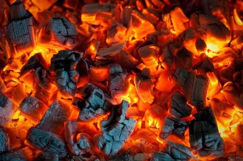 Glowing orange and red embers from a hot charcoal fire