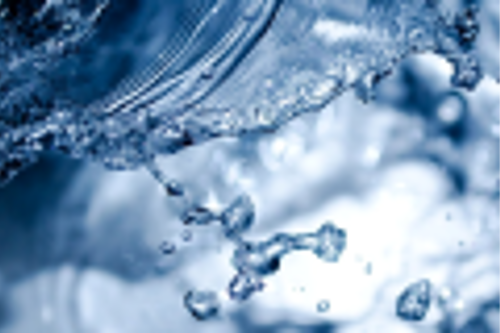 Close-up view of clear water splashing with droplets captured in motion against a blurred blue background